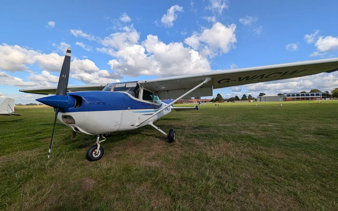 Our blue and white Cessna 172, G-WACW, parked on the grass at Rochester Airport